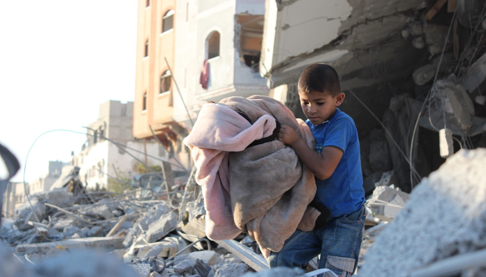 A Gaza un enfant extirpe une couverture d'un immeuble complément détruit - image par Hosny Salah, photographe palestinien résidant actuellement en Palestine, dans la bande de Gaza, pour Pixabay